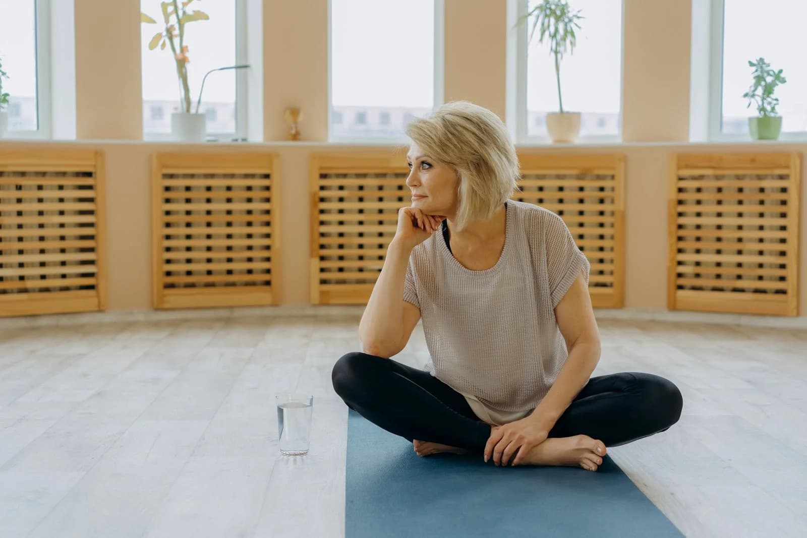 Uma mulher idosa sentada em um tapete de yoga indoors, refletindo pacificamente. Perfeito para conceitos de bem-estar e fitness, ilustrando espiritualidade sem dogma