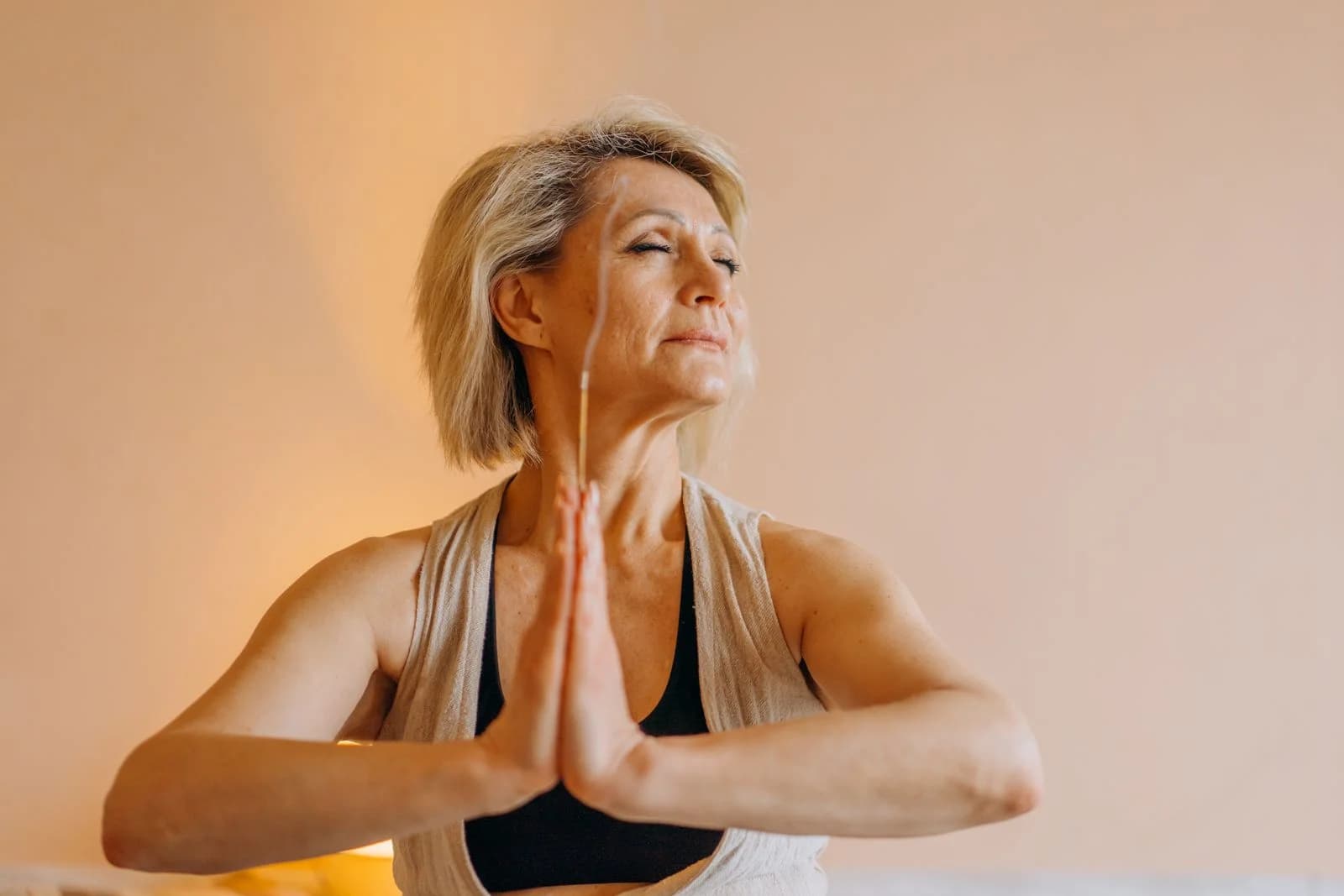 Uma mulher idosa meditando em um ambiente interno com os olhos fechados, demonstrando tranquilidade mental, ilustrando rituais de conexão sem religião específica