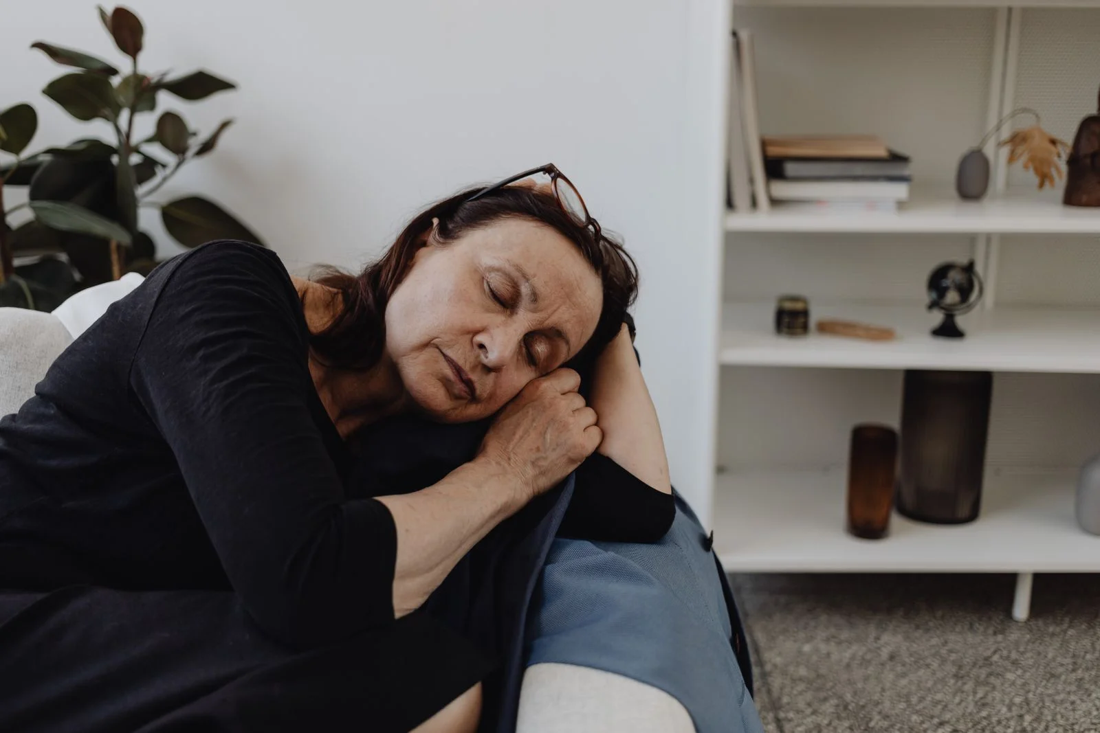 Mulher idosa vestindo roupas casuais dormindo em um sofá com uma expressão serena dentro de casa, ilustrando regras para uma soneca estratégica sem prejudicar o sono noturno
