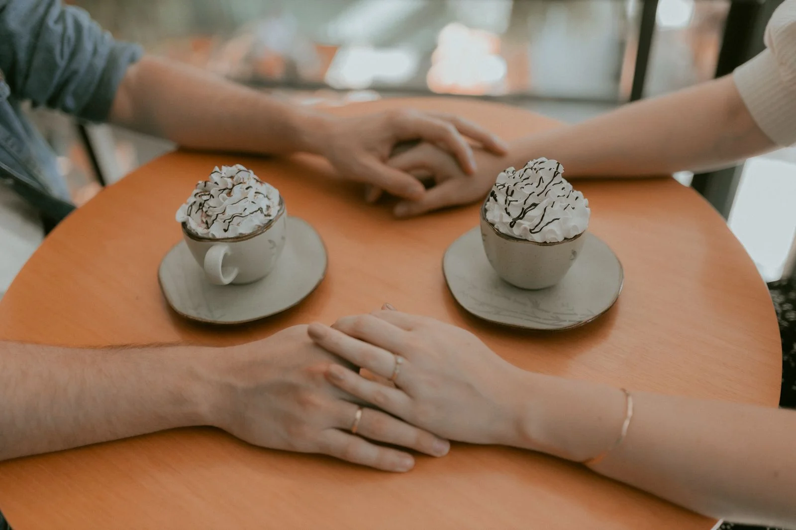 Casal de mãos dadas tomando chocolate quente em um aconchegante café, ilustrando expectativas e realidade de voltar a se relacionar