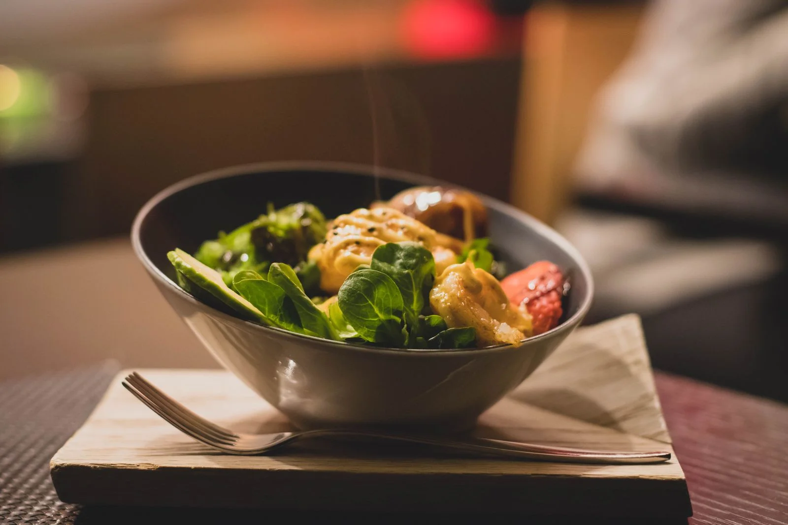 Deliciosa tigela de salada com verduras frescas e frango grelhado servido em uma bandeja de madeira, ilustrando alimentação anti-inflamatória na menopausa