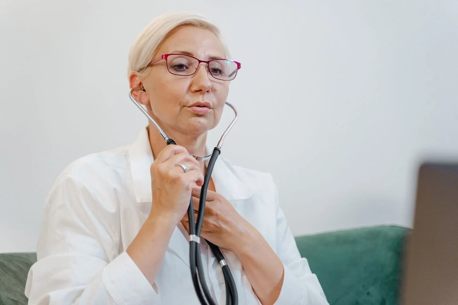 Doutora idosa usando um estetoscópio durante uma consulta virtual em um consultório médico, ilustrando como diferenciar ansiedade hormonal de outros quadros