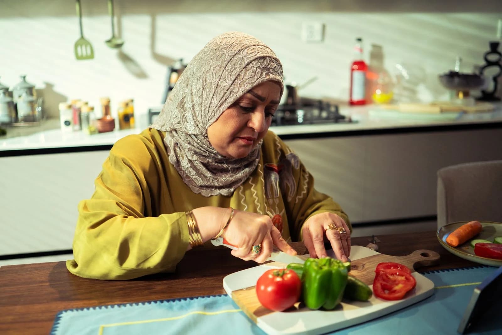 Mulher do Oriente Médio preparando uma refeição, cortando legumes em uma cozinha moderna, ilustrando estratégias para o metabolismo mais lento na menopausa