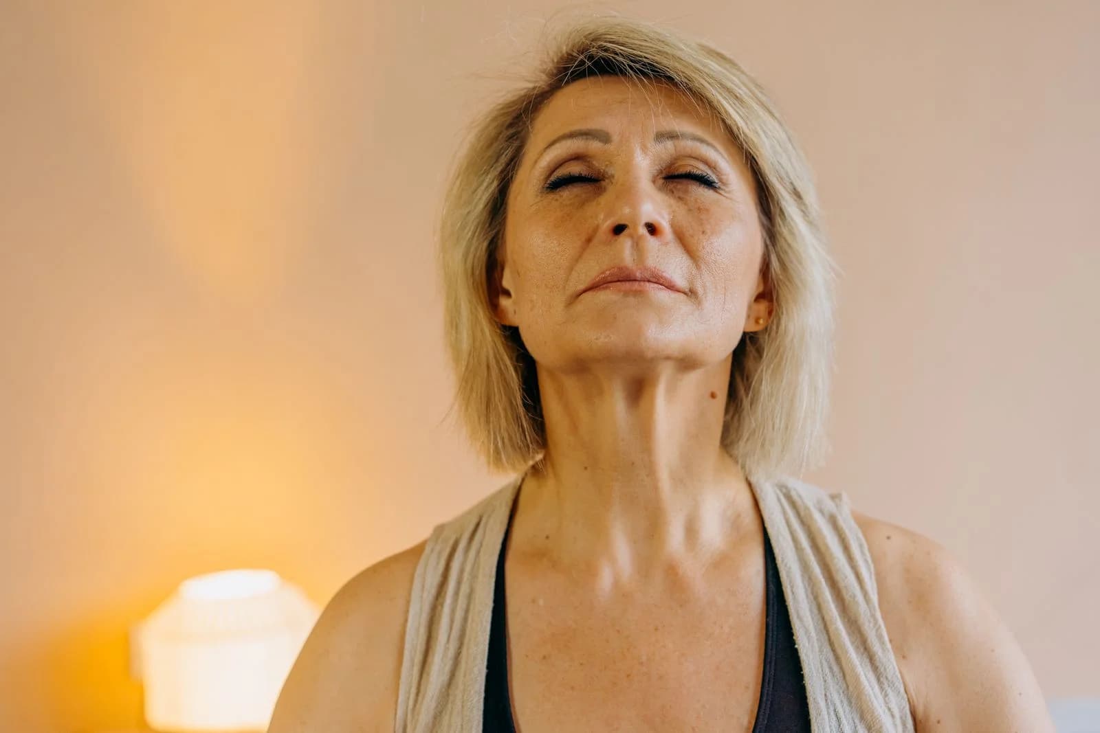 Mulher idosa serena praticando mindfulness em casa, olhos fechados em paz e relaxamento, ilustrando estratégias para picos de irritabilidade na menopausa