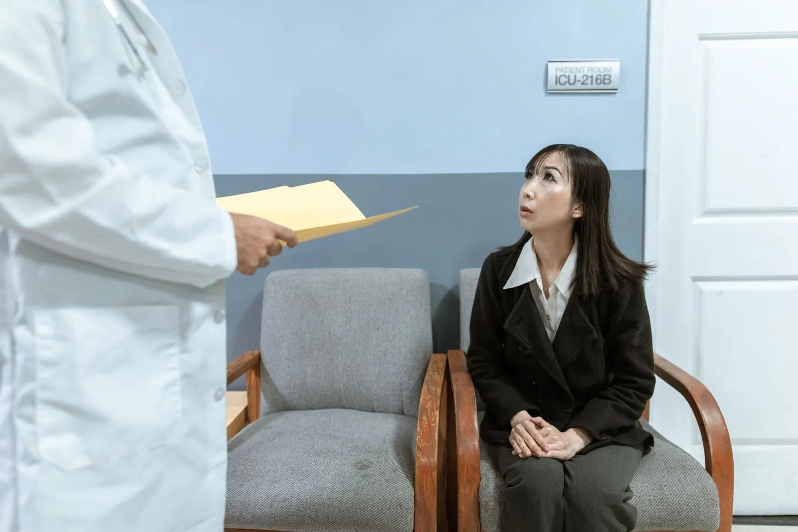 A worried woman seated in a hospital waiting room, interacting with a doctor, ilustrando sinais de que os fogachos estão piorando